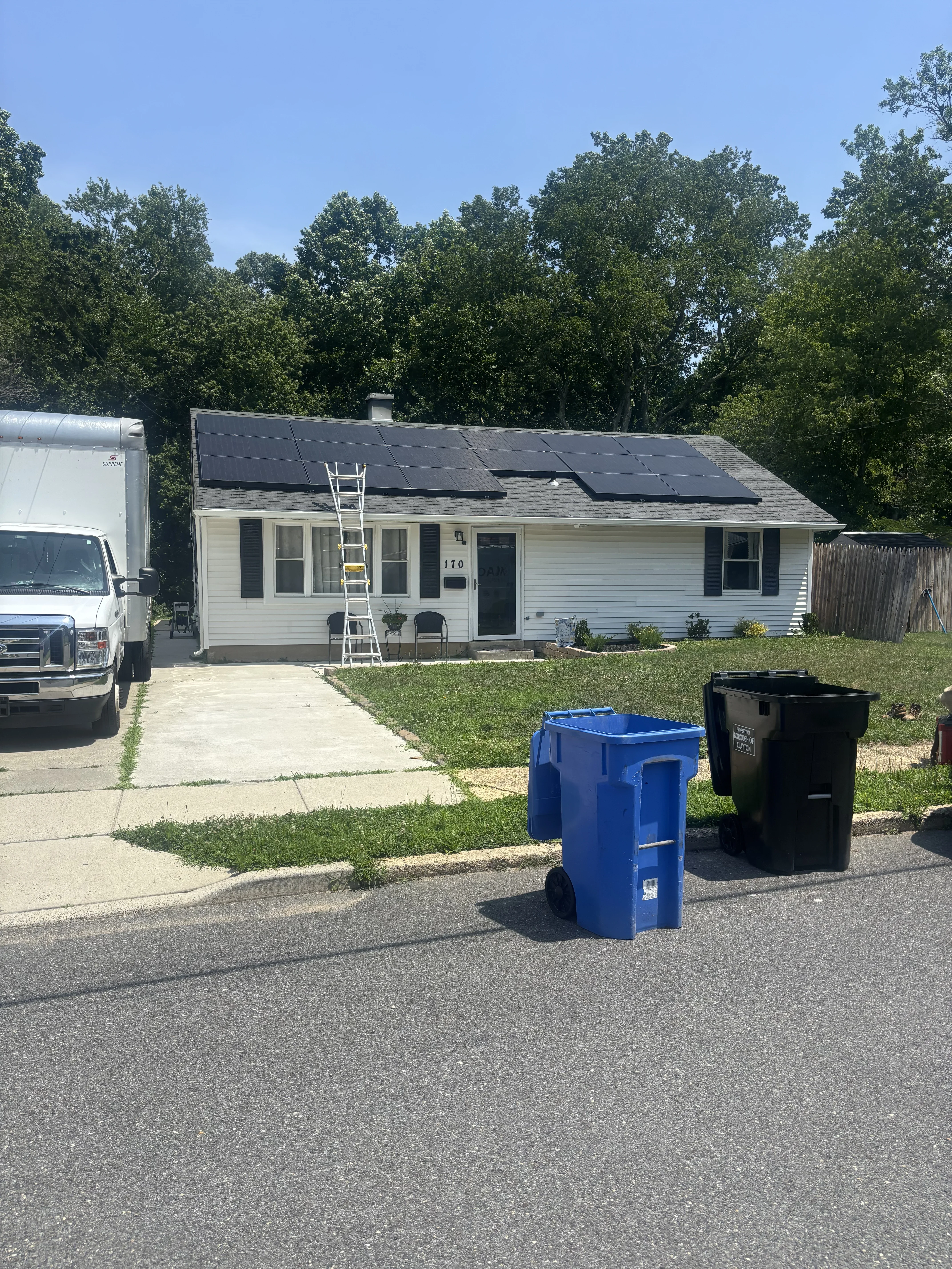 Black solar panels installed on residential roof with white vinyl siding and asphalt shingles