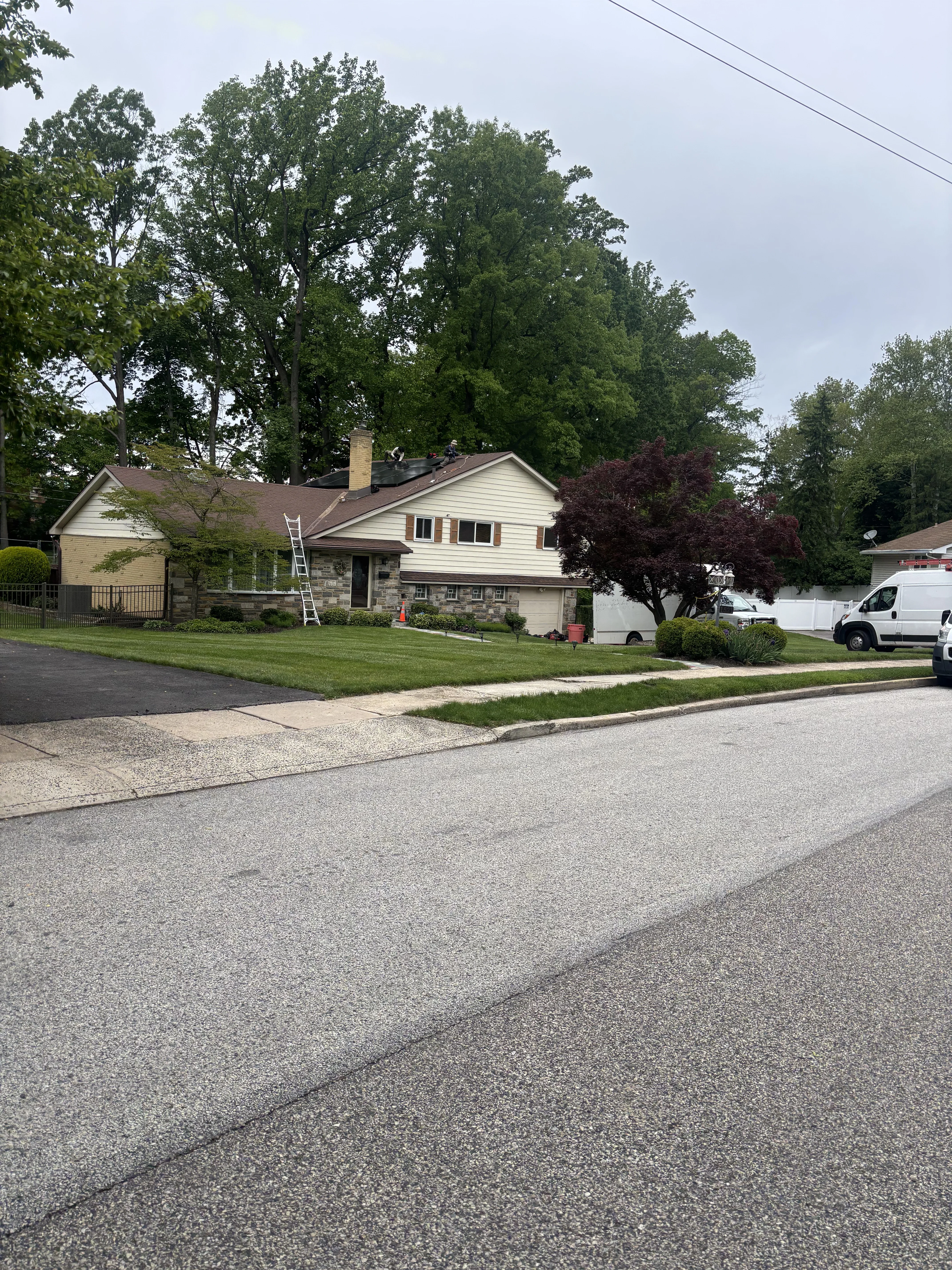 Solar panels installed on residential home roof with white siding and stone accents